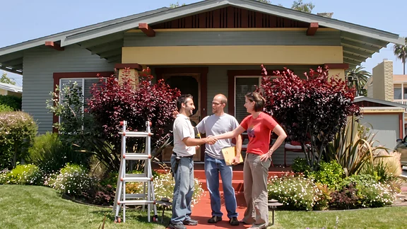 An inspector handing over the findings to buyers outside a San Diego bungalow
