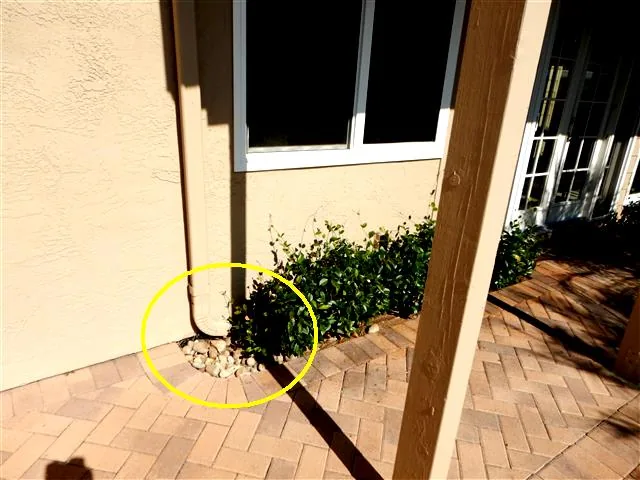 Downspout discharging beside the house