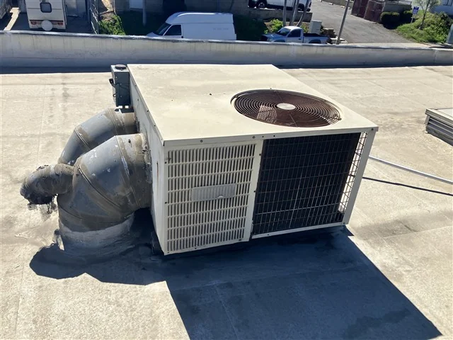 A rooftop packaged air conditioning unit and its flexible ductwork on a commercial roof