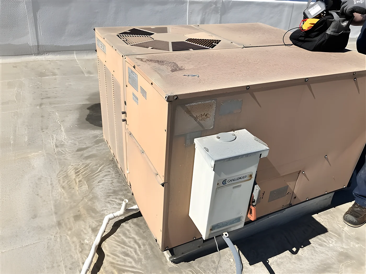 An inspector at an opened rooftop packaged HVAC unit during a commercial field assessment