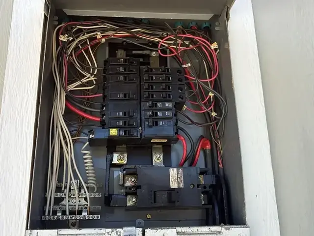 Exterior main panel open at the door, breakers, feeders and the circuit directory