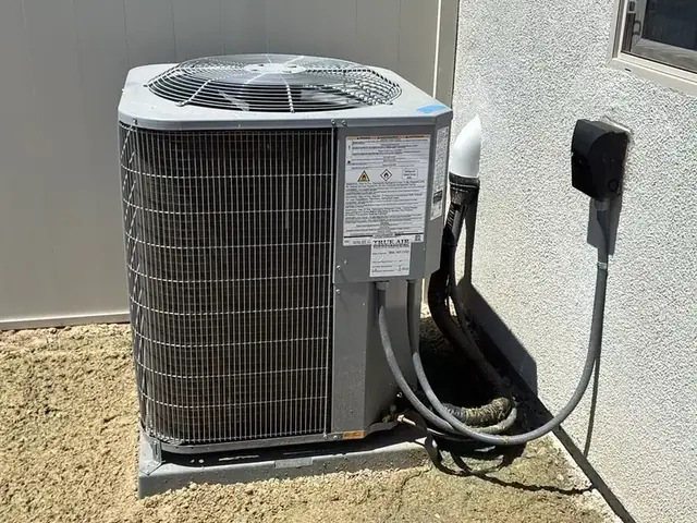 Outdoor condensing unit on its pad at the side of the house