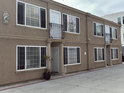 Front elevation of a two-story stucco condominium building in San Diego with decorative iron balconies on the second floor