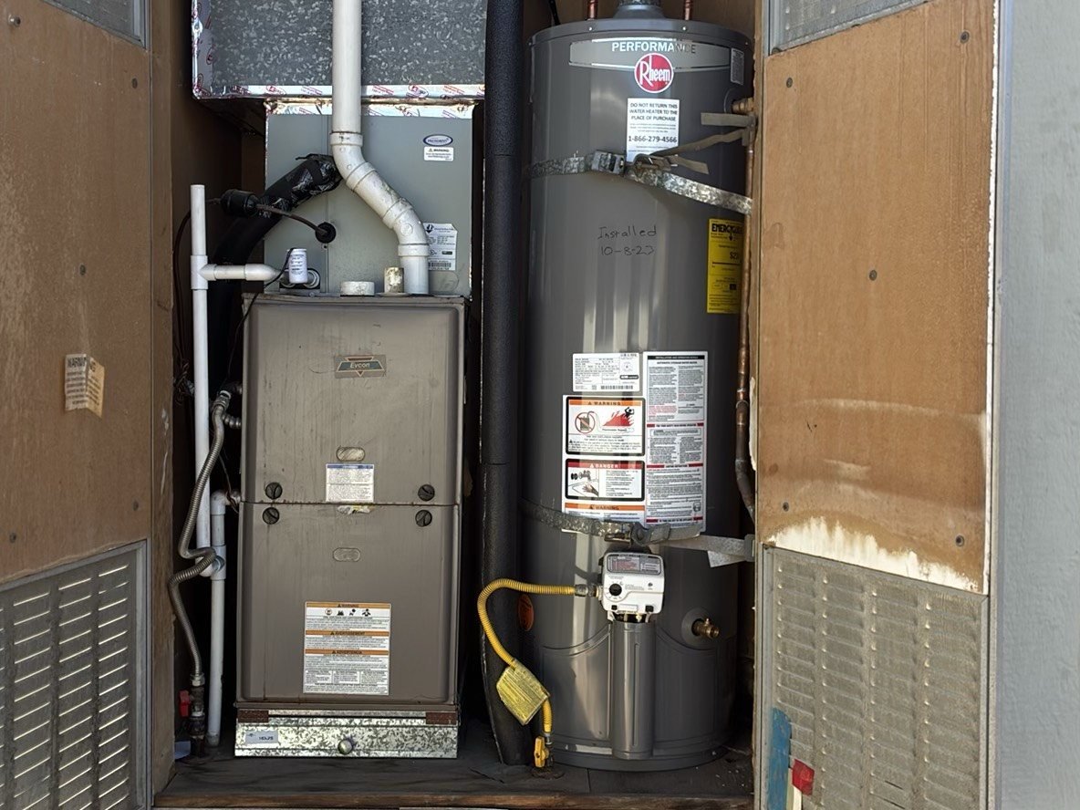 Interior utility closet showing a gas furnace (HVAC air handler) alongside a Rheem Performance gas water heater with earthquake straps, yellow gas flex line visible