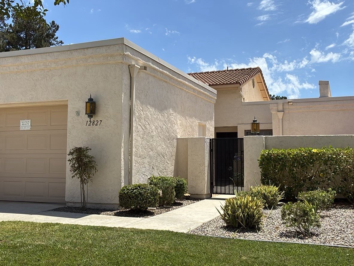 Front exterior of a stucco home with tile roof, iron gate, and lush front yard landscaping in San Diego