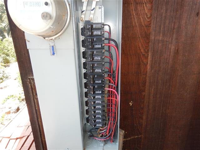 Outdoor electrical sub-panel with organized red and black wiring and circuit breakers