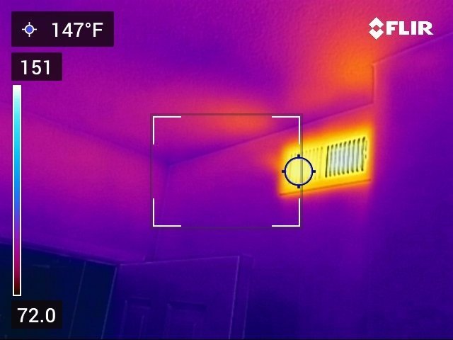 FLIR thermal image of a ceiling heating register glowing bright orange and yellow against a deep purple background, temperature reading 147 degrees Fahrenheit