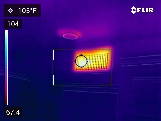 Infrared view of a ceiling heat register showing intense orange-yellow heat output at 105 degrees Fahrenheit against a cool blue-purple ceiling