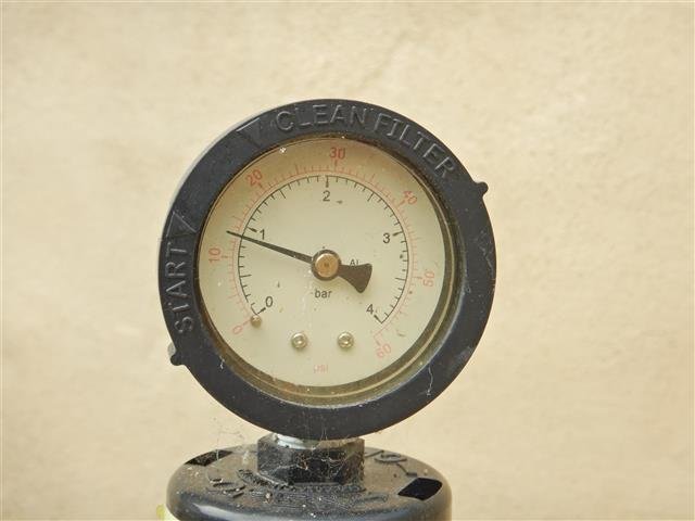 Close-up of a pool filter pressure gauge showing PSI and bar readings with START and CLEAN FILTER indicators on the bezel