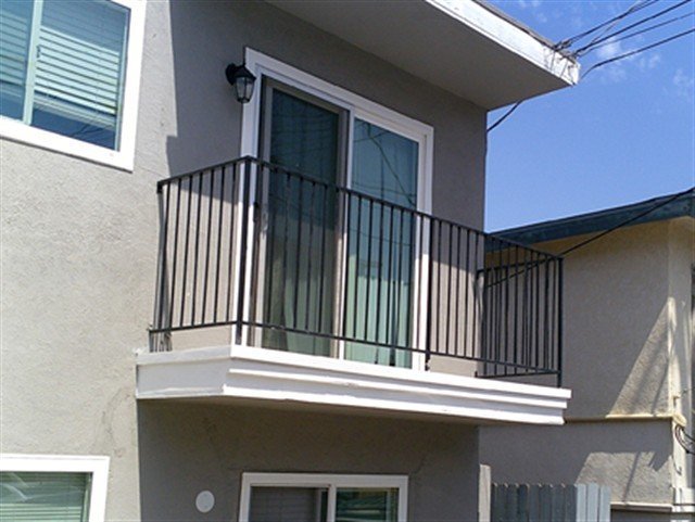 Clean private balcony with black steel vertical-bar guardrails on stucco apartment building