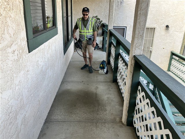 Inspector spraying water on an apartment walkway during a drainage test