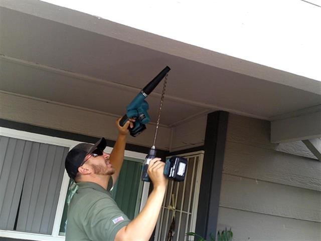 Inspector drilling a balcony soffit access hole