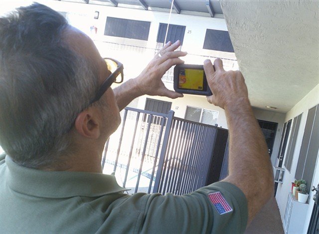 Inspector holding a thermal camera overhead on an exterior walkway
