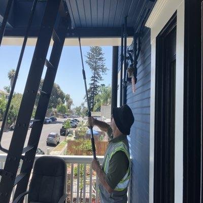 Inspector using a pole tool on a porch ceiling during an SB 721 inspection